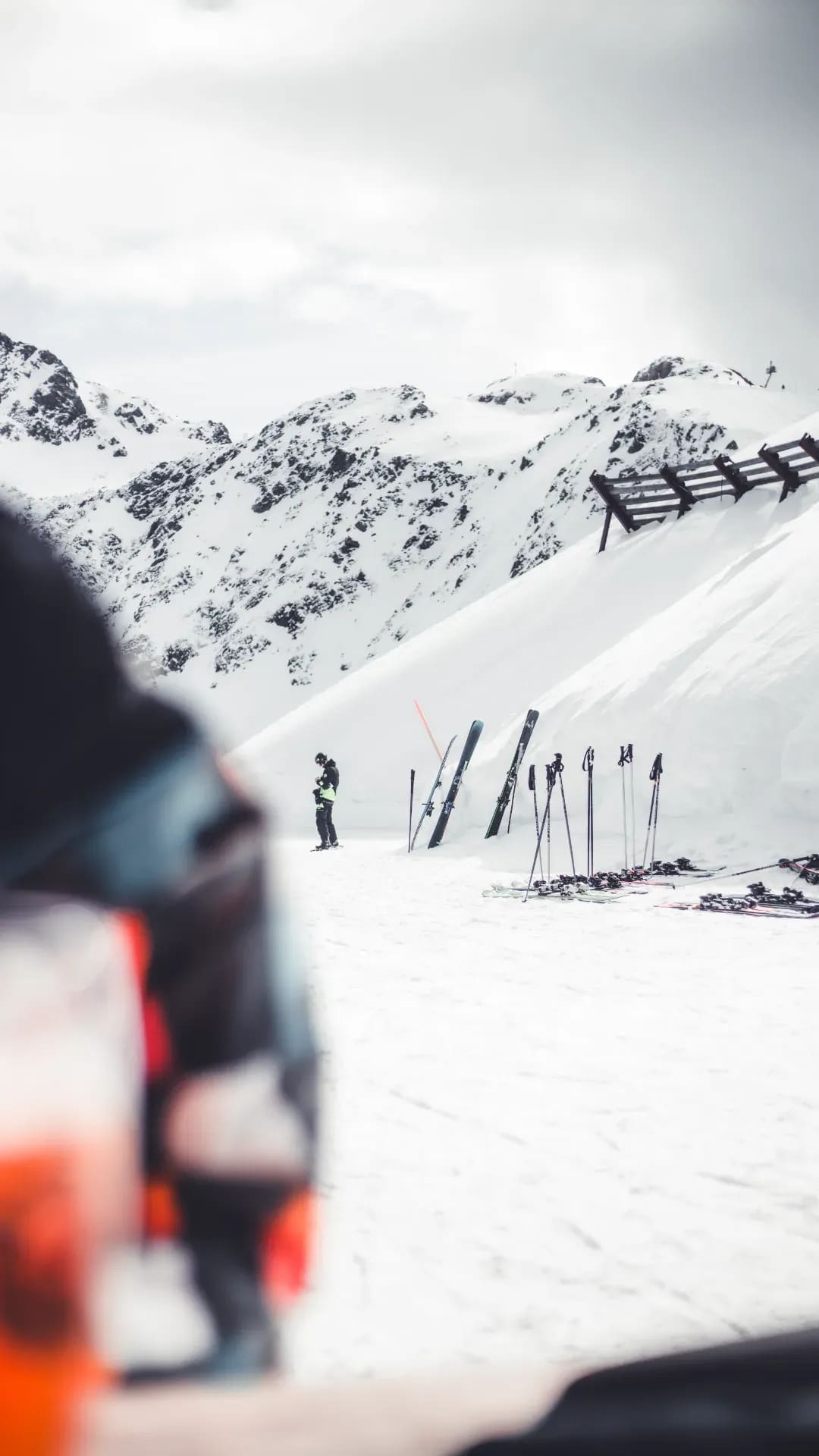 Blick über eine Schulter auf abgestellte Ski am Pistenrand